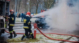 Samochód uderzył w budynek, straż walczy z płomieniami